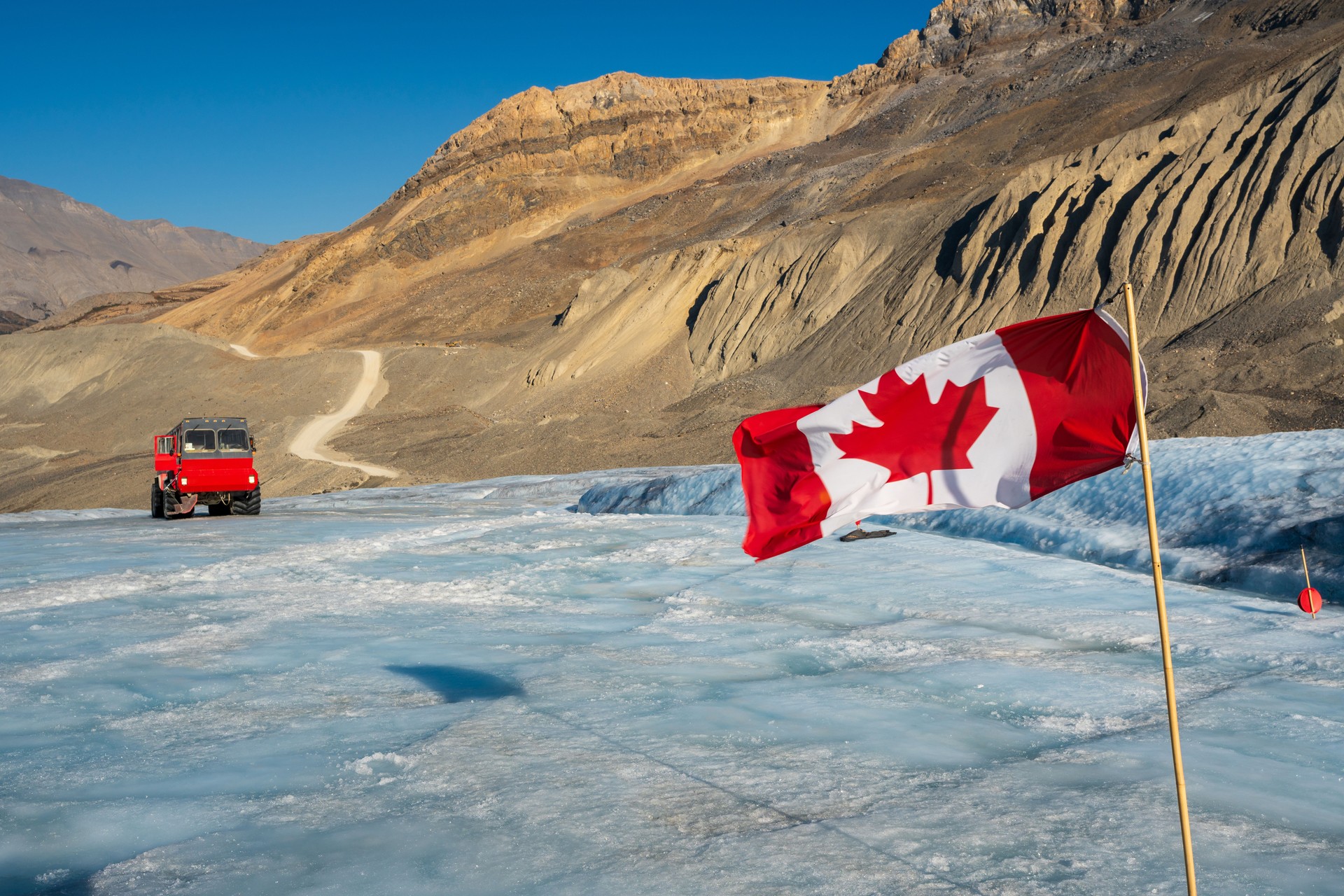 Canadian flag and Ice explorer vehicle on Columbia Icefield, Jasper National Park, Alberta, Canada.